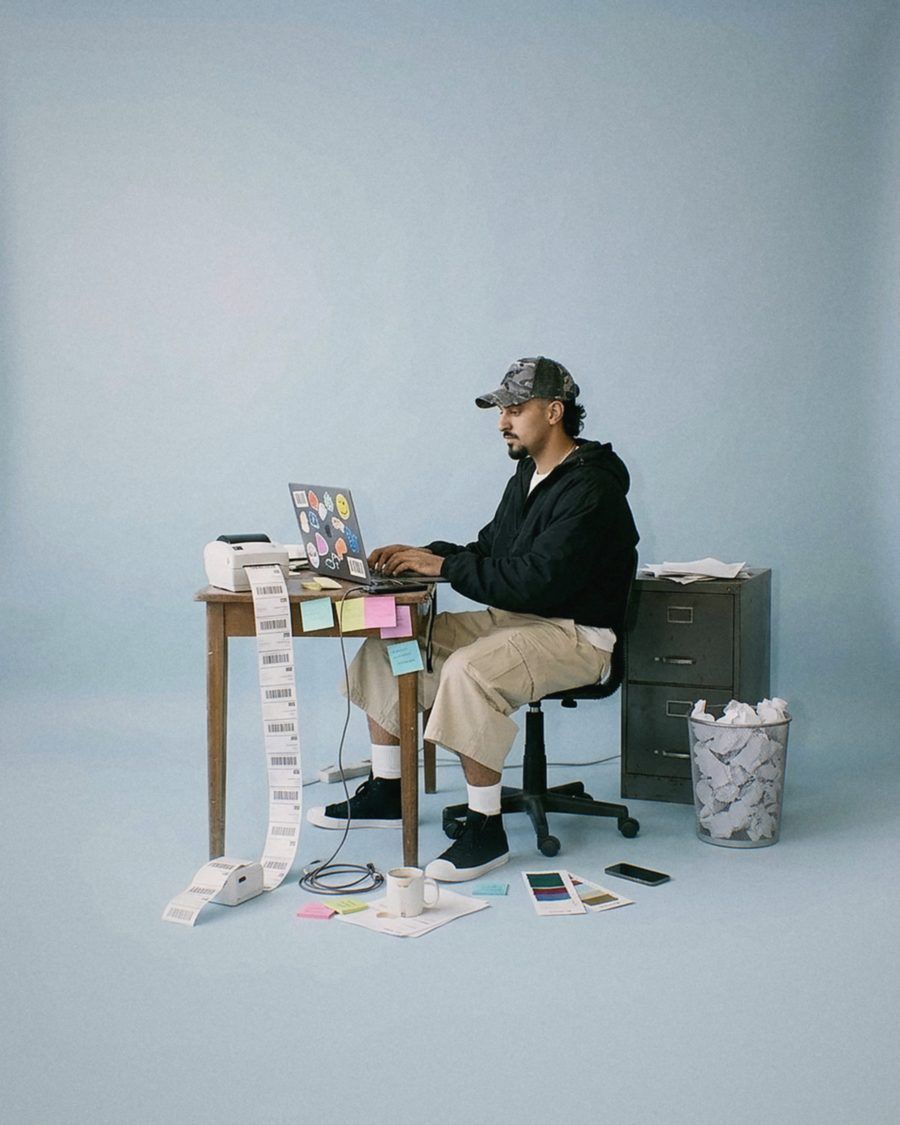 A founder typing at a small desk with labels spilling to the floor